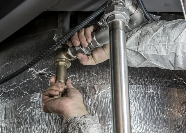 Plumber fitting a new pipe section during a leak repair