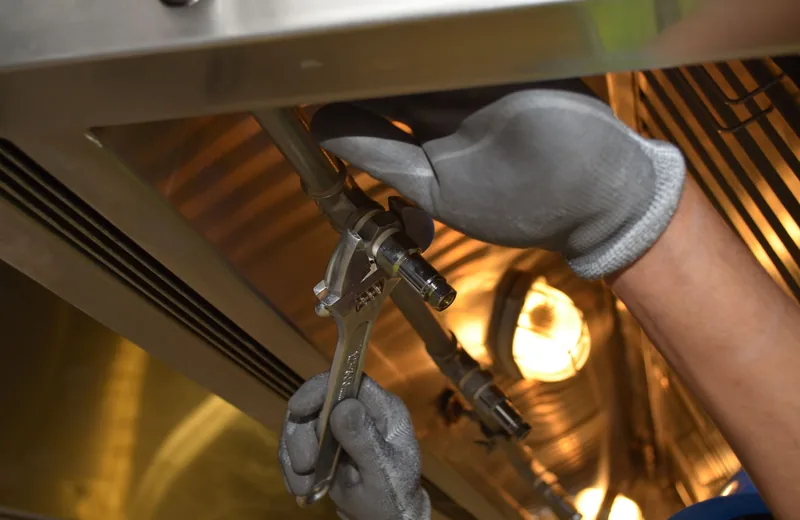 Plumber tightening a pipe fitting with a wrench during leak repair