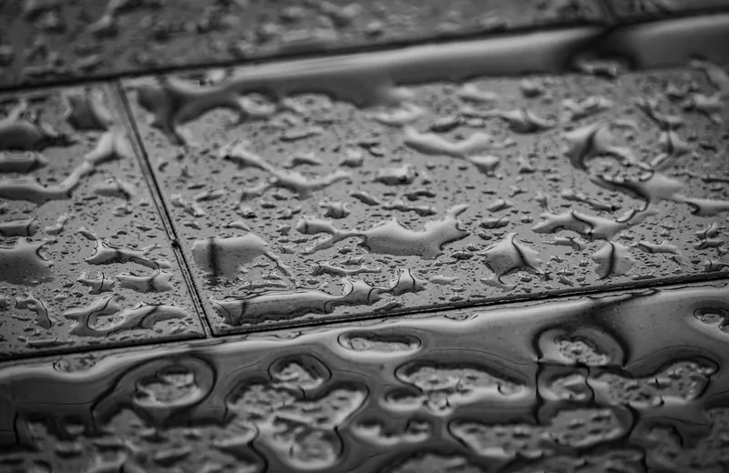 Water beading on a tiled floor above a slab leak