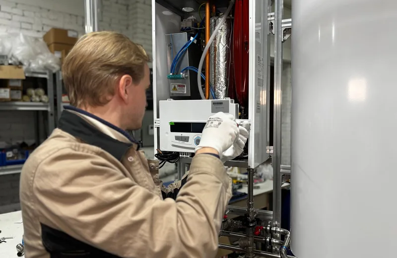 Technician checking water heater fittings and supply lines for leaks