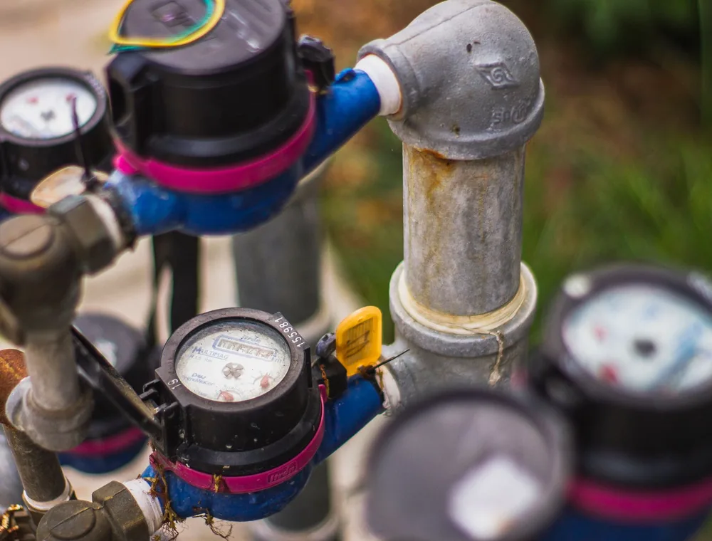 Water meters spinning on a line with a hidden leak behind a high water bill
